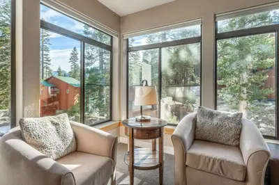 a living room with two chairs and a table and large windows at Silver Bear 32 in Mammoth Lakes