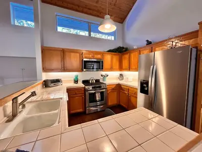 a kitchen with wooden cabinets and a stainless steel refrigerator at Cozy Mammoth Ski Condo with Mtn Views and Hot Tub in Mammoth Lakes
