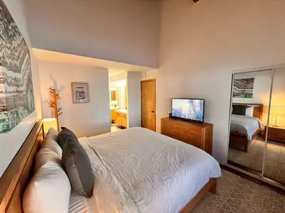 a bedroom with a large bed and a television at Cozy Mammoth Ski Condo with Mtn Views and Hot Tub in Mammoth Lakes