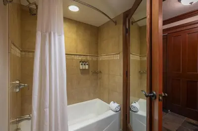 a bathroom with a tub and a shower with a shower curtain at Ski-InandSki-Out! 2BR Condo with Resort Pools, Spa in Olympic Valley