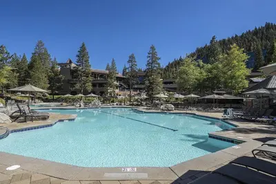 a large swimming pool with chairs and umbrellas at Ski-InandSki-Out! 2BR Condo with Resort Pools, Spa in Olympic Valley