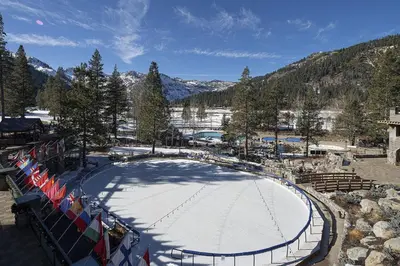 an ice skating rink in a ski resort with flags at Walk to Palisades Tahoe Ski Lifts Mtn-View Condo in Olympic Valley