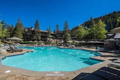 a large pool with chairs and umbrellas in a resort at Sweeping Views and Access to Slopes Everline Condo in Olympic Valley
