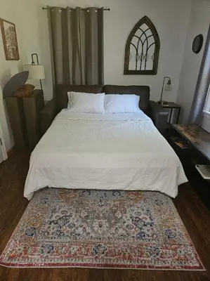 a bedroom with a large bed with a rug on the floor at Amador Wine Country Cottage in Fiddletown