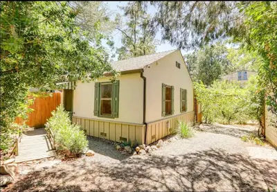 a small yellow house with a fence and trees at Amador Wine Country Cottage in Fiddletown