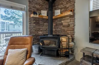 a stone fireplace in a living room with a leather chair at Chateau Blanc 1 in Mammoth Lakes