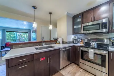 a kitchen with wooden cabinets and stainless steel appliances at Quaint 1B/1BA Canyon Lodge Condo: Jacuzzi & More! in Mammoth Lakes