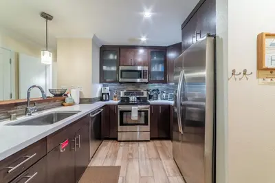 a kitchen with wooden cabinets and stainless steel appliances at Quaint 1B/1BA Canyon Lodge Condo: Jacuzzi & More! in Mammoth Lakes