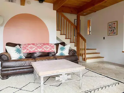 a living room with a brown leather couch and stairs at Casa Manzanita in Midpines! 26 miles to Yosemite! in Midpines