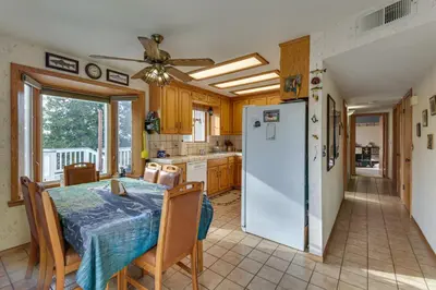 a kitchen with a table and a refrigerator at Deck and Wooded Views 5-Acre Auberry Retreat! in Auberry