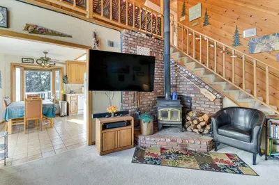 a living room with a fireplace and a flat screen tv at Deck and Wooded Views 5-Acre Auberry Retreat! in Auberry