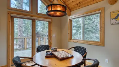 a dining room with a table and chairs and windows at Truckee Mountain Cabin with Hot Tub Game Room Forest Views Gray Wolf Lodge by AvantStay in Truckee