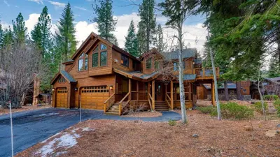 a large wooden house with a garage at Truckee Mountain Cabin with Hot Tub Game Room Forest Views Gray Wolf Lodge by AvantStay in Truckee