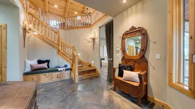 a living room with a staircase and a mirror at Truckee Mountain Cabin with Hot Tub Game Room Forest Views Gray Wolf Lodge by AvantStay in Truckee