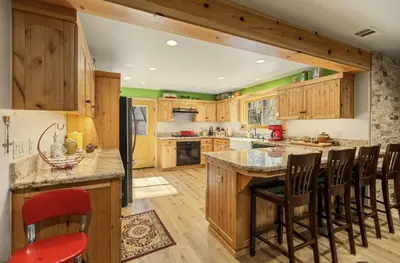 a kitchen with wooden cabinets and a island with bar stools at Big Foot Hide Out Shaver Lake Mts in Shaver Lake