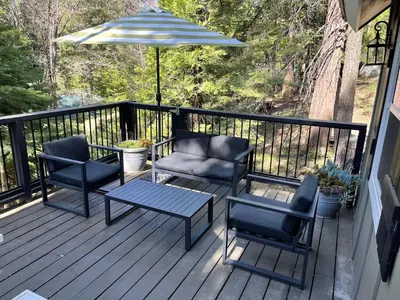a deck with two chairs and a table and an umbrella at The Little Dipper Cabin in Shaver Lake