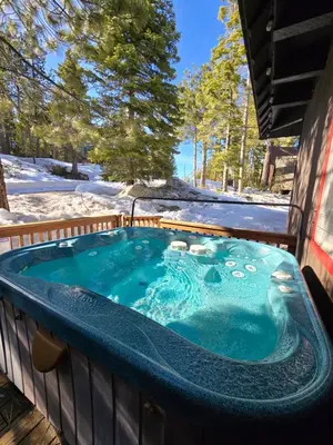 a jacuzzi tub on a deck in the snow at Chamberland retreat-Hot Tub, Pool Table, Movie & Ski in Homewood