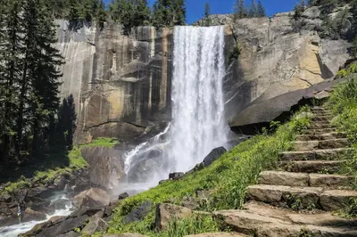a waterfall on the side of a mountain with stairs at Strawberry Chalet Near Pinecrest & Dodge Ridge in Strawberry