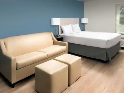 a hotel room with a bed and a couch at WoodSpring Suites Manteca - Stockton South in Manteca