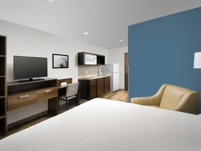 a hotel room with a bed and a desk with a television at WoodSpring Suites Manteca - Stockton South in Manteca