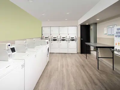 a laundry room with white cabinets and a table at WoodSpring Suites Manteca - Stockton South in Manteca