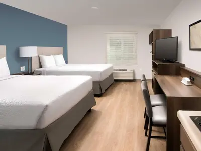 a hotel room with two beds and a desk at WoodSpring Suites Manteca - Stockton South in Manteca