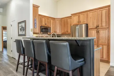 a kitchen with wooden cabinets and a bar with stools at Snowcreek 704 in Mammoth Lakes