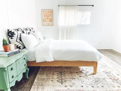 a bedroom with a bed with a wooden bed frame and a table at Yosemite Boho Bungalow, Pet Friendly & Mtn Views! in Coarsegold