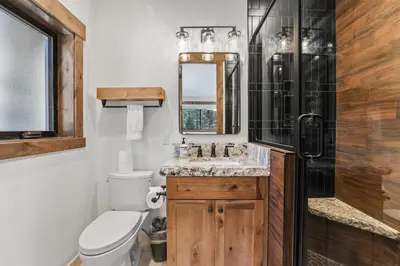 a bathroom with a sink and a toilet and a mirror at Paradise on Pioneer - New 6 Bedroom w Pool Table in South Lake Tahoe