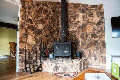 a stone wall with a stove in a room at Sierra Cabin w NEW Hot Tub Walk to Town in Twain Harte