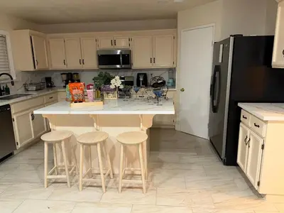a kitchen with a island with stools and a black refrigerator at Vineyard inspired house in stockton in Stockton