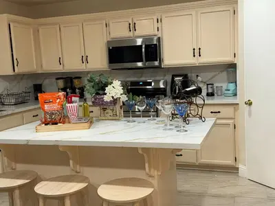 a kitchen with a large white island with stools at Vineyard inspired house in stockton in Stockton