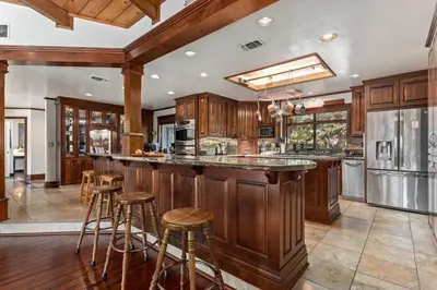 a kitchen with wooden cabinets and a bar with stools at Cozy Lake View 4Bd 2,5Br Retreat in 5 Acres, Hot Tub and more in Auburn
