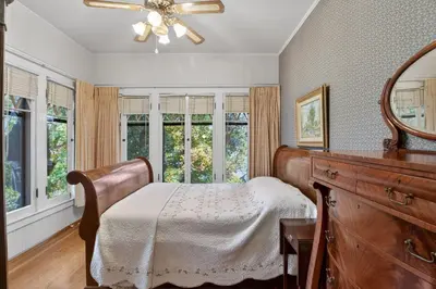 a bedroom with a bed and a mirror and windows at The Spalding House Comfort in Visalia home in Visalia