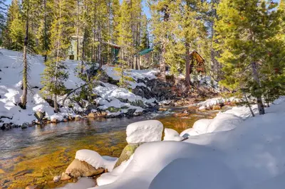 a river in a snowy forest with snow covered trees at Steps From Sledding Hill! Soda Springs Mtn Retreat in Soda Springs
