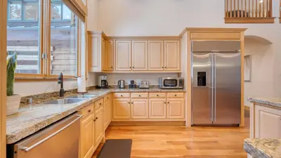 a kitchen with wooden cabinets and a stainless steel refrigerator at 2 Truckee Cabin • Sleeps 20 • Hot tub • Games • Near Donner Lake Donner Ridge Alplenglow Chalet by AvantStay in Truckee