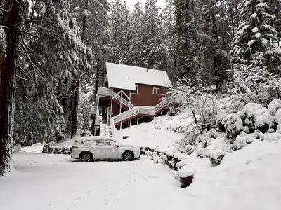 a car parked in front of a house covered in snow at Half Dome Haven - Cozy Yosemite West Studio in Yosemite West