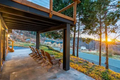 a group of chairs sitting on a porch with the sunset at Dogwood Retreat- Family friendly Epic Views in Shaver Lake