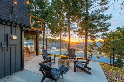 a patio with chairs and a table with a view of the water at Dogwood Retreat- Family friendly Epic Views in Shaver Lake