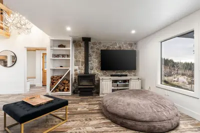 a living room with a tv and a large ottoman at Dogwood Retreat- Family friendly Epic Views in Shaver Lake