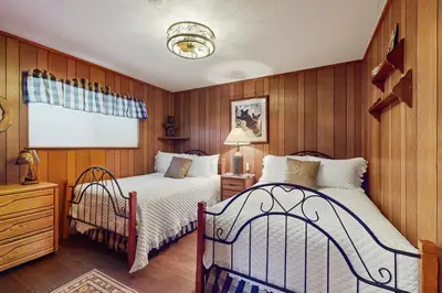 two beds in a room with wood paneling at Cabin on the Green in South Lake Tahoe