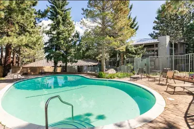 a swimming pool in a yard with chairs and trees at Sierra Park Villas 28 in Mammoth Lakes