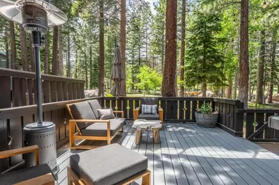 a deck with chairs and an umbrella in the woods at Timbers 1057 in Mammoth Lakes