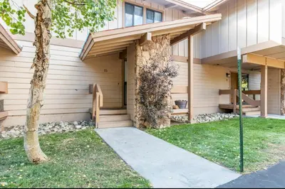 a building with a tree next to a sidewalk at Villa De Los Pinos 15 in Mammoth Lakes