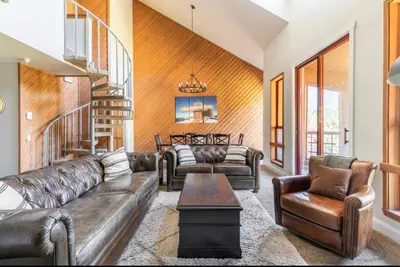 a living room with leather furniture and a staircase at Aspen Creek 230 in Mammoth Lakes