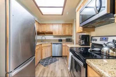 a kitchen with a stainless steel refrigerator and wooden cabinets at Aspen Creek 230 in Mammoth Lakes