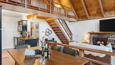 a dining room with a table and a fireplace at Hot Tub • Firepit • Loft Suite Mins to World-Class Skiing Tahoe A-Frame Retreat by AvantStay in Carnelian Bay