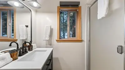 a white bathroom with a sink and a mirror at Hot Tub • Firepit • Loft Suite Mins to World-Class Skiing Tahoe A-Frame Retreat by AvantStay in Carnelian Bay
