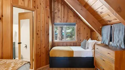 a bedroom in a log cabin with a bed and a window at Hot Tub • Firepit • Loft Suite Mins to World-Class Skiing Tahoe A-Frame Retreat by AvantStay in Carnelian Bay