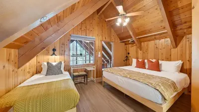 two beds in a room with wooden walls at Hot Tub • Firepit • Loft Suite Mins to World-Class Skiing Tahoe A-Frame Retreat by AvantStay in Carnelian Bay